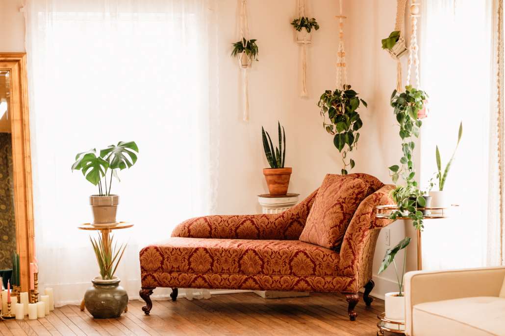 Vintage-inspired photography set at MI Studio Space featuring a rust-colored velvet chaise lounge, hanging macrame plant holders, and a gold floor mirror surrounded by white candles.