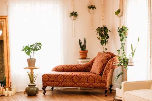 Vintage-inspired photography set at MI Studio Space featuring a rust-colored velvet chaise lounge, hanging macrame plant holders, and a gold floor mirror surrounded by white candles.