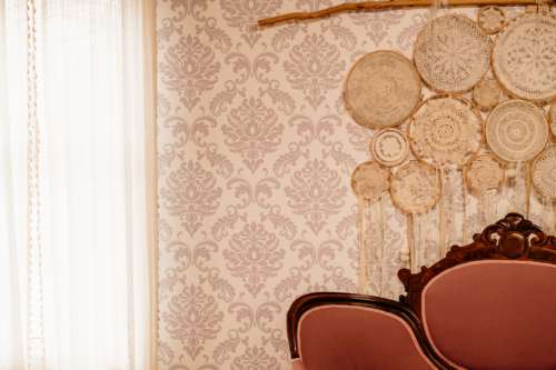 Vintage photography set at MI Studio Space featuring a Victorian-style wood-trimmed sofa, patterned damask wallpaper, and a unique wall installation of delicate lace embroidery hoops.