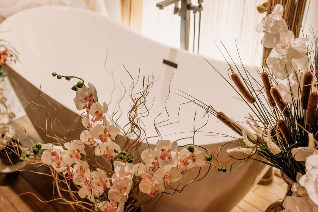 Detail shot of a white vintage clawfoot bathtub at MI Studio Space, decorated with overflowing white orchids, dried pampas grass, and floral stems.