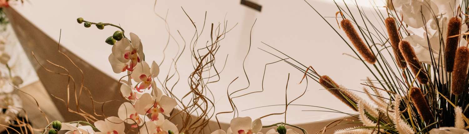 Detail shot of a white vintage clawfoot bathtub at MI Studio Space, decorated with overflowing white orchids, dried pampas grass, and floral stems.