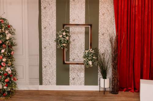 Dramatic photography set at MI Studio Space featuring deep red velvet curtains, a floral-adorned floating picture frame, and vintage-style patterned wallpaper